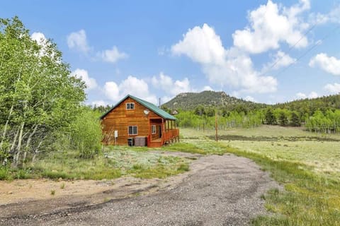 Private Cabin with a spacious porch in open meadow and tree-covered hills.