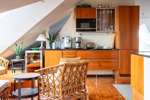 Wake up to natural light streaming into this open-plan space, complete with a well-equipped kitchen, coffee station, and comfortable chairs — ideal for slow mornings or relaxing evenings in.