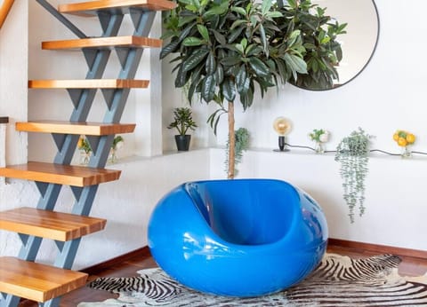 A sleek floating staircase leads upstairs, while the iconic Finnish Pilleri chair adds a bold pop of color to the space.