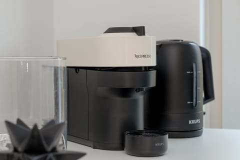 A capsule coffee machine and electric kettle on a countertop. The appliances suggest a convenient setup for making hot drinks.