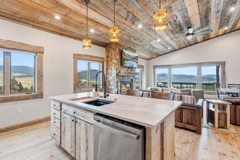 Gather loved ones in this stunning open kitchen where rustic wood beams frame breathtaking mountain views through floor-to-ceiling windows.