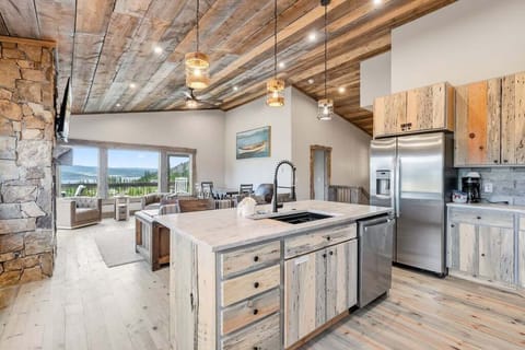 Cook with mountain views in this rustic-elegant kitchen featuring reclaimed wood, stone fireplace, and modern appliances.