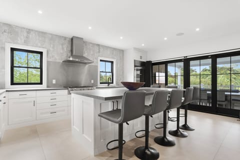 Kitchen with island eating features fully equipped pot, pans cutlery and plates.