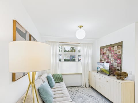 Cozy living room with stylish decor, comfortable sofa, 32" smart TV, and natural light