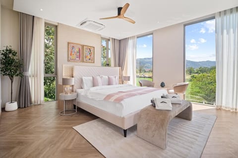 Bright master bedroom with panoramic windows, comfortable queen bed, and warm interior tones.