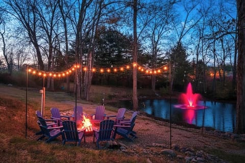 Magical backyard firepit scene w/ string lights & forest views for memorable nights outside.