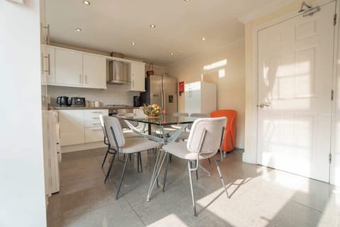Bright and welcoming kitchen-dining area with modern appliances and a stylish glass table for shared meals.