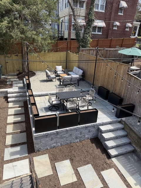 Modern tiered patio with lounge seating, dining, and string lights