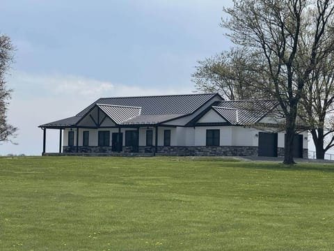 This close-up view highlights the beautiful architectural design and bold contrast of the black metal roof and stone accents.
The wide porch and symmetrical layout give the home a clean and inviting presence.