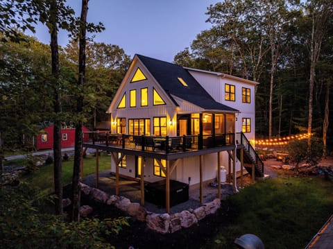 Twilight exterior with expansive deck & glowing A-frame windows