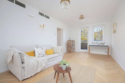 The bright living room with a large window and elegant parquet invites you to relax in natural light, creating a warm and homely atmosphere.