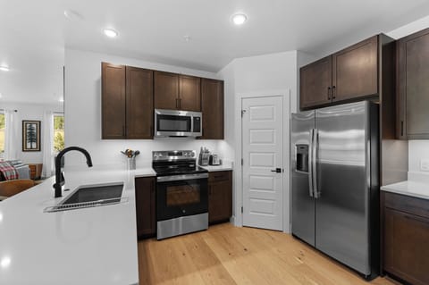 Full kitchen with stainless steel appliances, and breakfast bar seating three.