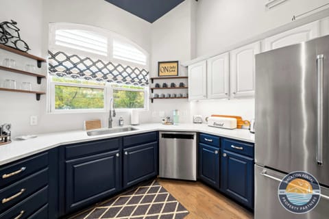 Gourmet chef's kitchen featuring dark navy custom cabinetry, quartz countertops, stainless steel appliances, and a spacious island. Modern design with all amenities for preparing memorable meals