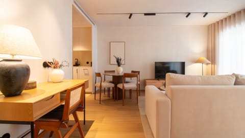 Elegant open-plan living space featuring a modern TV setup, round dining table, and a stylish workspace—perfect for work and relaxation. #PortoApartment #WorkFriendlyStay #ModernDesign