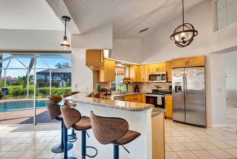 Kitchen | Granite Breakfast Bar, Stainless Steel Appliances, and Poolside View