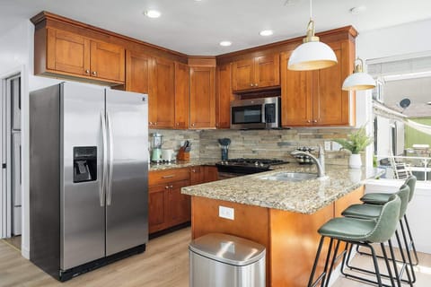 Prepare your favorite meals in a fully equipped kitchen featuring sleek appliances, beautiful wood cabinetry, and a cozy breakfast bar.