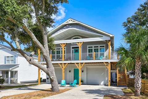 Modern coastal home featuring bright turquoise accents and tropical landscaping in a peaceful residential setting.