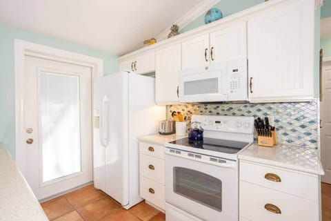 Airy open-concept kitchen, coastal backsplash shining—your AMI hub for easy meals.