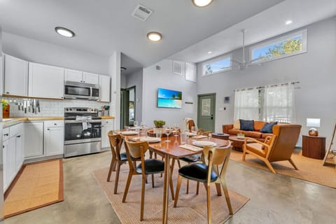 Bluebonnet Lodge full kitchen with 6 person dining table, comfy couch and chairs next to a 65` TV