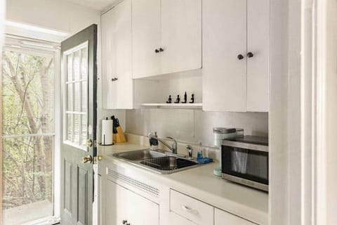 A clean, full kitchen with white cabinets, a sink, microwave, stove, and toaster—perfect for preparing meals. The windowed door lets in natural light, creating a bright and welcoming space for your culinary needs.