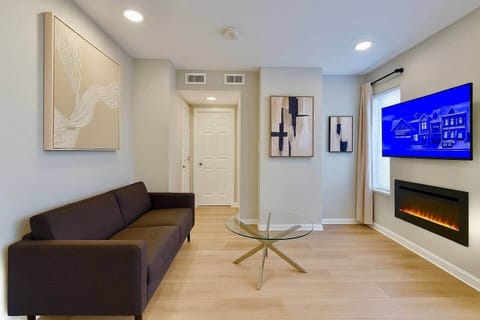 Cozy modern living room with a futon sofa, flatscreen TV, and electric fireplace for a warm, relaxing stay.