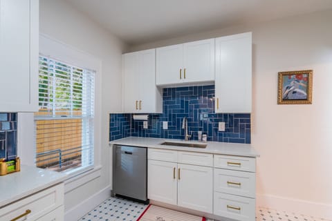 Modern kitchen with white cabinetry, sleek stainless steel appliances, and a vibrant blue tile backsplash.