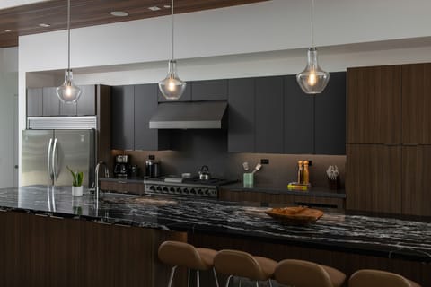 The chef's island kitchen features a stainless steel gas range, professional hood, and gorgeous black marble countertops.