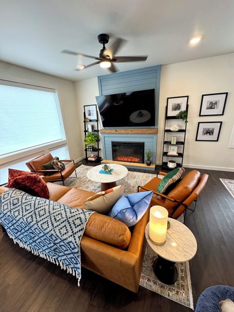 Living room area with all leather seating, fireplace, and 72" Roku TV.