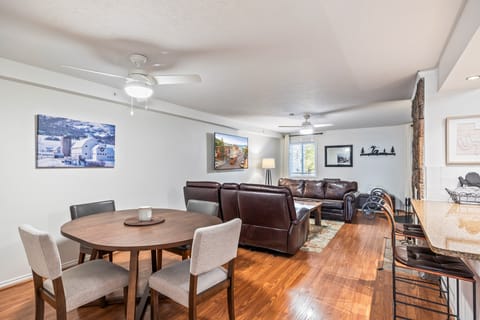 A bright, open living area featuring plush leather couches, mountain-themed artwork, Open Living and Dining Spaceand beautiful hardwood floors. Perfect for relaxing or gathering after a day of skiing and exploring.