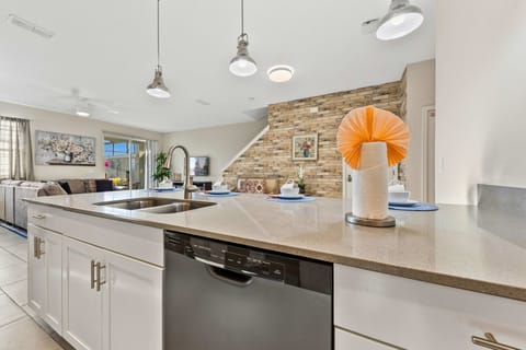 Bright open-concept island with sink and dishwasher, pendant lighting, and views to the living area-perfect for cooking while staying connected.