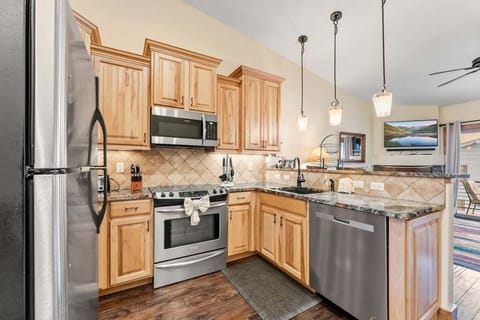 Your fully equipped kitchen invites culinary adventures with granite counters, stainless appliances, and warm wood cabinets creating the perfect cooking space.