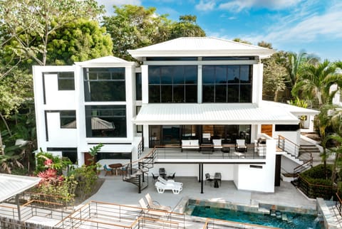 Modern luxury villa surrounded by lush jungle, featuring expansive terraces and a private pool.