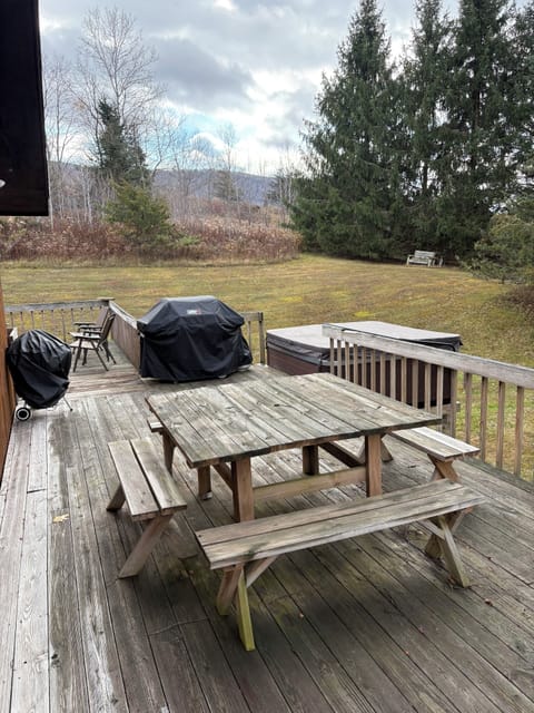 Wraparound deck with grill, dining table, and hot tub.