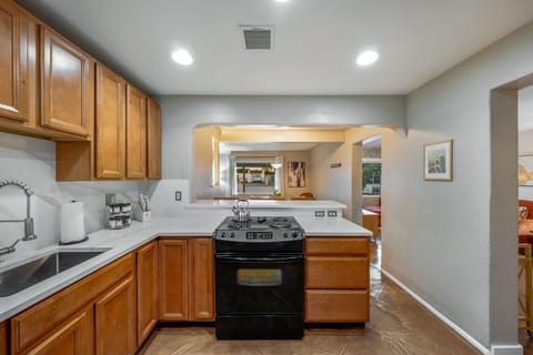 Fully equipped kitchen with warm wood cabinetry, tiled backsplash, and modern appliances for all your cooking needs