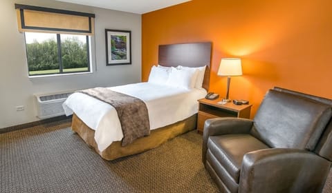 Recharge on a crisp king bed beside a cozy armchair.