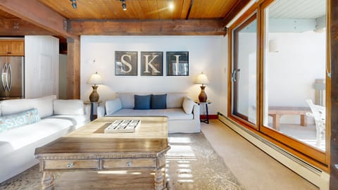 Relax in your stylish living space where rustic wood beams meet modern comfort, complete with cozy seating and terrace access.