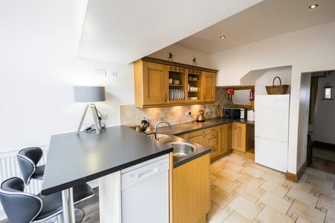 Kitchen with breakfast bar, two stools, fridge freezer, kettle, cafetiere and microwave