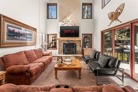 Spacious living room with vaulted ceilings, large smart TV, fireplace and walkout patio