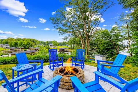 Fire Pit - Six blue chairs circle a crackling fire on the stamped patio, made for evening s'mores with a water view.