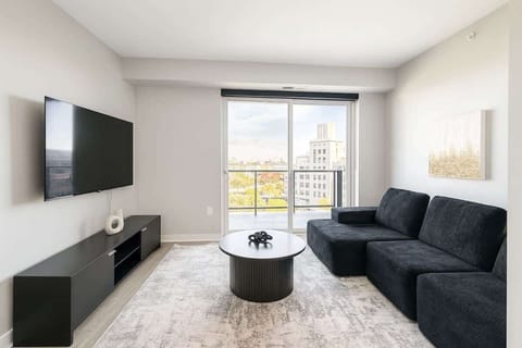 Bright and airy living area featuring floor-to-ceiling windows, plush sectional seating, and skyline views of Uptown Minneapolis.