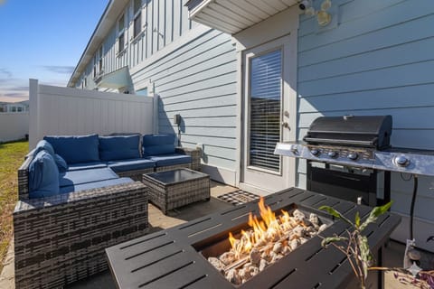 Private outdoor patio with comfortable lounge seating, fire pit table, and BBQ g