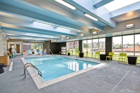 Unwind poolside in a sunlit indoor oasis with lounge seating.