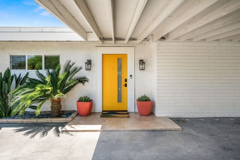 Cheerful yellow front door under a covered carport—your modern desert welcome.