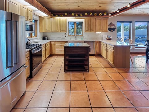 Step into your dream kitchen where rustic charm meets modern convenience. Cook family meals with top-of-the-line stainless steel appliances while admiring the exposed wooden beams and warm sunflower accents above.