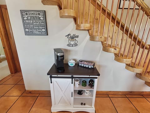 Start your mornings right with this charming coffee station tucked perfectly beneath the rustic wooden staircase. Your personal Keurig awaits to brew that perfect cup while you plan your day's adventures.