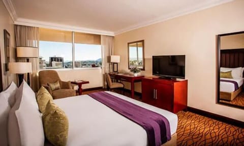 Unwind on crisp linens while city views glow outside.