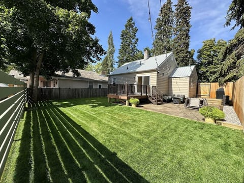 Spacious fenced backyard with open green lawn and large deck for outdoor enjoyment.