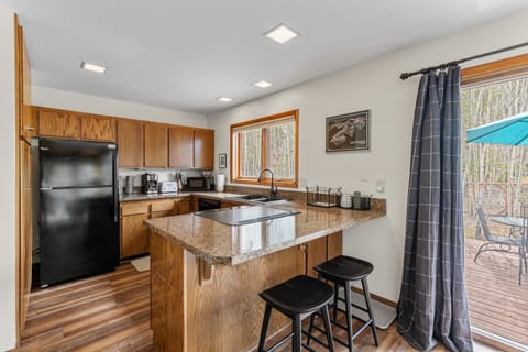 Fully-equipped kitchen with stainless steel fridge and forest views.