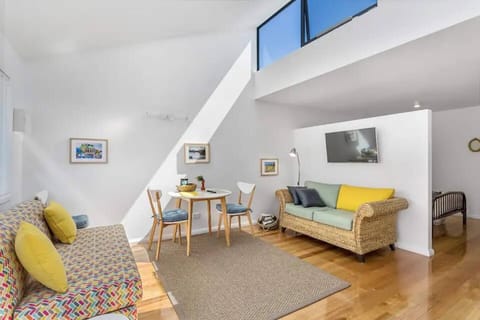 Experience relaxation in the cozy living room, complete with comfortable seating and a wall-mounted smart TV. A small dining table caters to meals at home.