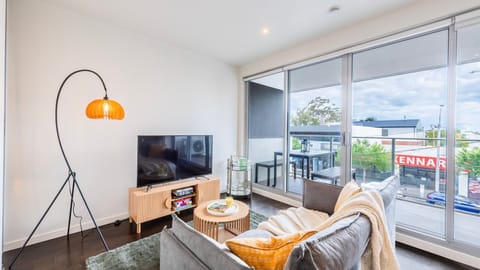 Bright and cozy living area with a flat-screen TV and natural light streaming in through the windows.